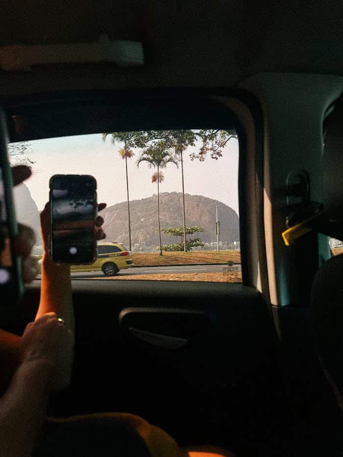 Mujer tomando foto con móvil en el asiento trasero de un taxi
